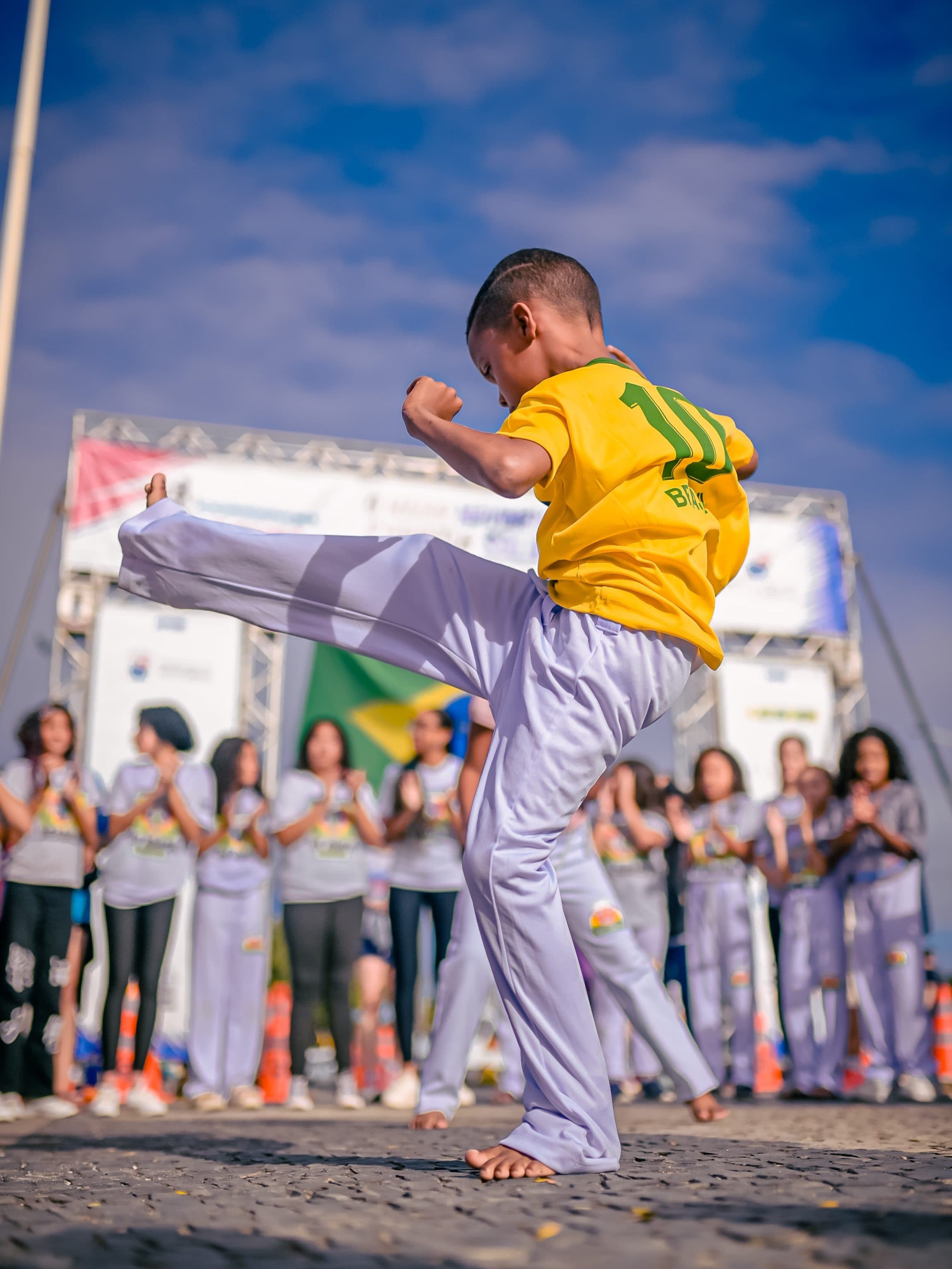 Criança do Instituto Vovô Chiquinho jogando capoeira diante das outras crianças